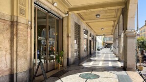 En överbyggd gångväg med ett klinkergolv, butikslokaler och ett kafé som heter ”CAFEROYAL”.