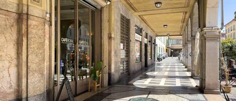 Un pasillo cubierto con suelo de baldosas, locales comerciales y una cafetería llamada 'CAFEROYAL'.