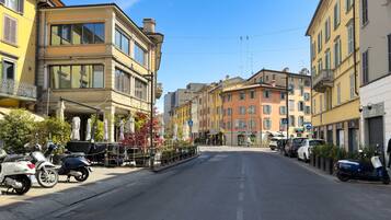 Eine Straße mit geparkten Rollern und Autos, Gebäude mit Balkonen und einem klaren Himmel.