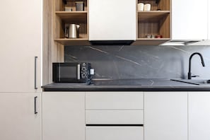 A modern kitchen with a black countertop, a built-in microwave, a stainless steel kettle, and a black faucet. - Città Studi: Two-room apartment near the M2 Piola station (Milan)