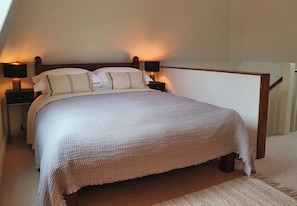 Un dormitorio con una cama, dos mesitas de noche y una mesilla.