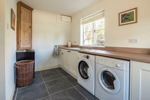 A laundry room with a washing machine, dryer, and a window with a view of greenery.