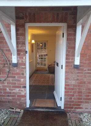 A brick entrance with a white door, a patterned rug, and a basket on the floor.