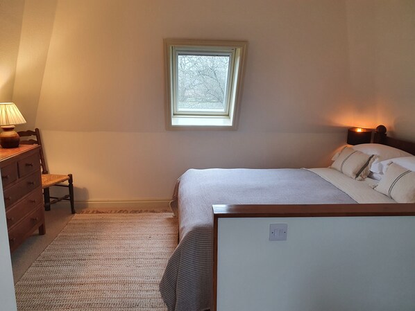 A bedroom with a bed, a nightstand, a dresser, a chair, and a window.