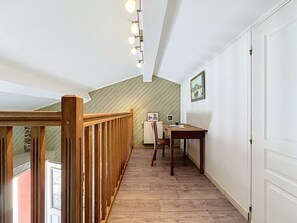 Eine Holztreppe führt zu einem Essbereich mit Tisch und Stühlen, einem Heizkörper und einem gerahmten Bild an der Wand.