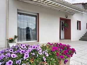 Ein Gebäude mit großem Fenster, einer Tür und einer kleinen Veranda mit Blumen.