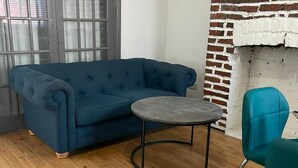 A room with a blue sofa, a round table, and a teal chair.