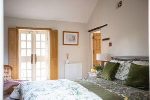 A bedroom with a bed, a radiator, a picture on the wall, and a door.