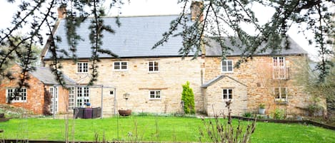 A stone house with a sloped roof, multiple windows, and a well-maintained lawn.