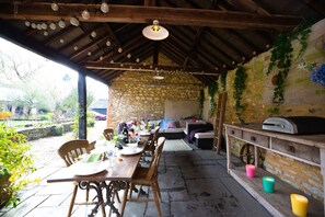 An outdoor patio with a stone wall, wooden furniture, and a grill station.