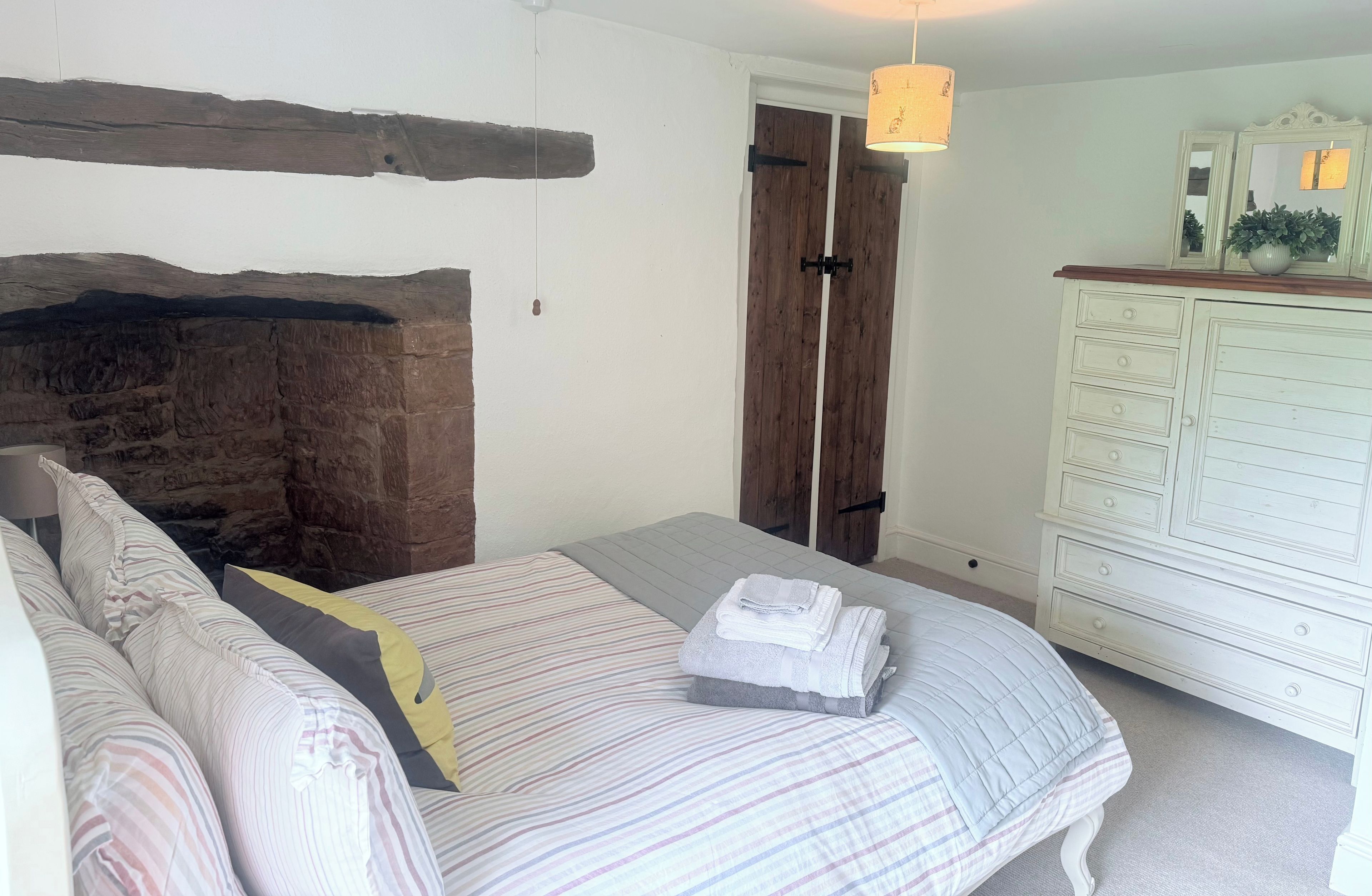 A bedroom with a bed, a dresser, and a hanging light fixture.