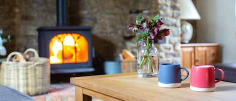 A cozy living room with a fireplace, a wooden coffee table, and a vase with flowers.