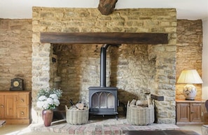 Una chimenea de piedra con un horno negro, flanqueada por cestas de mimbre y un armario de madera.