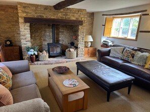 A cozy living room with a stone fireplace, leather sofa, and a wooden coffee table.