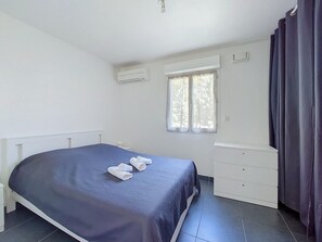 Ein Schlafzimmer mit Bett, Fenster, Kommode und Klimaanlage.