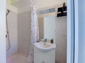 Ein Badezimmer mit Dusche, Waschbecken, Spiegel und Handtuchhalter.
