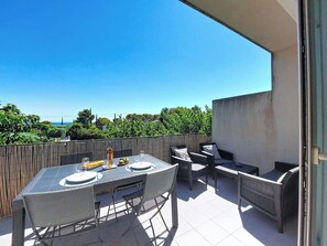 Eine Terrasse im Freien mit Tisch für zwei Personen, umgeben von Stühlen und einer Couch.