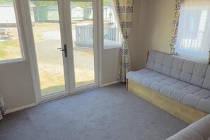 Une pièce comprenant un canapé, une porte-fenêtre coulissante donnant sur un espace extérieur et un rideau à motifs.
