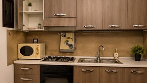 A kitchen with wooden cabinets, a microwave, a stove, a sink, and a small potted plant. - Modern Apartment in Alcamo near in Marina & Castellammare del Golfo (Alcamo)