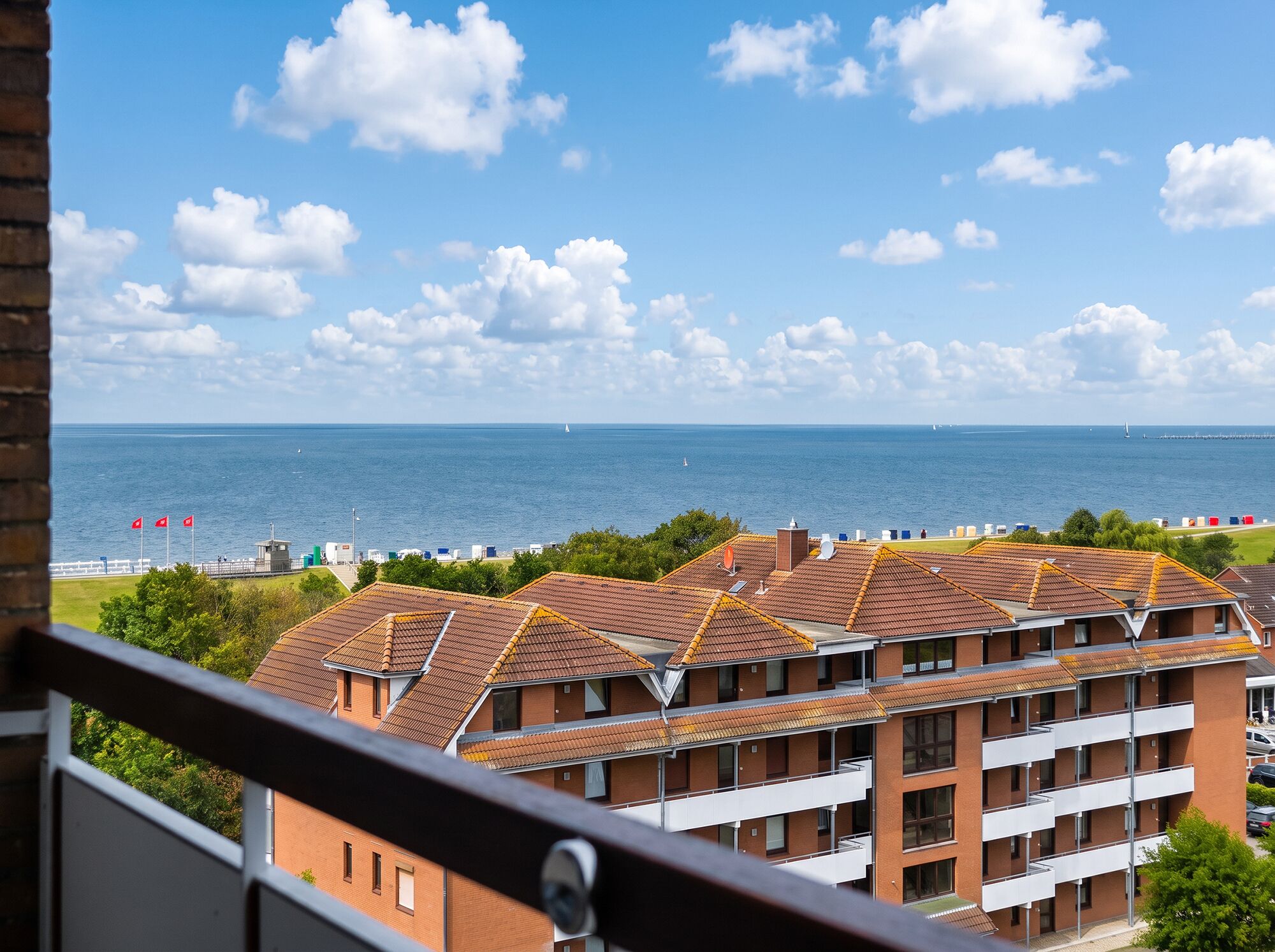 A residential building with multiple balconies overlooking a coastal area with a clear sky and sea.