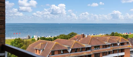 A residential building with multiple balconies overlooking a coastal area with a clear sky and sea.