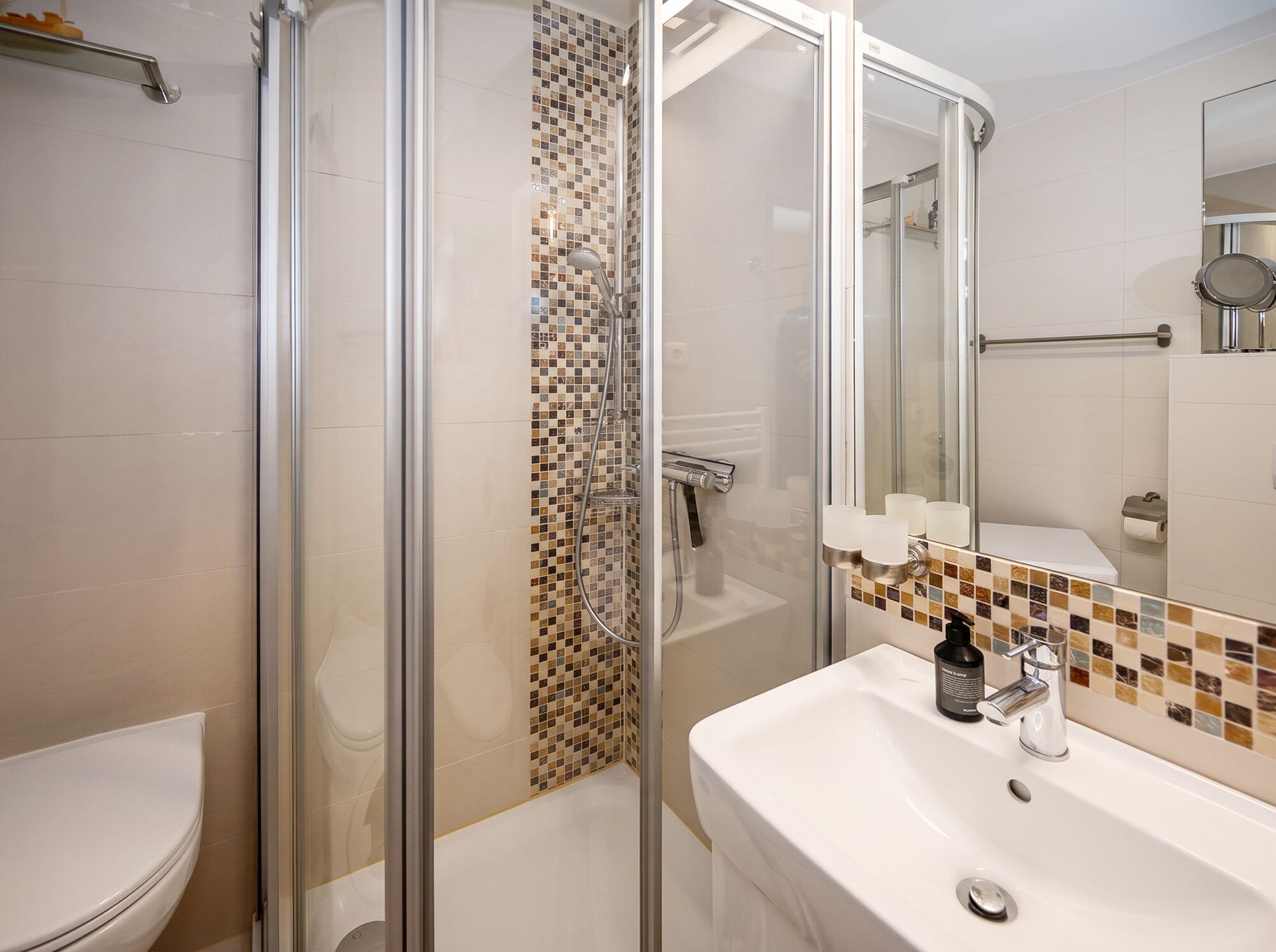 Uma casa de banho moderna com cabine de duche de vidro, lavatório branco e sanita.
