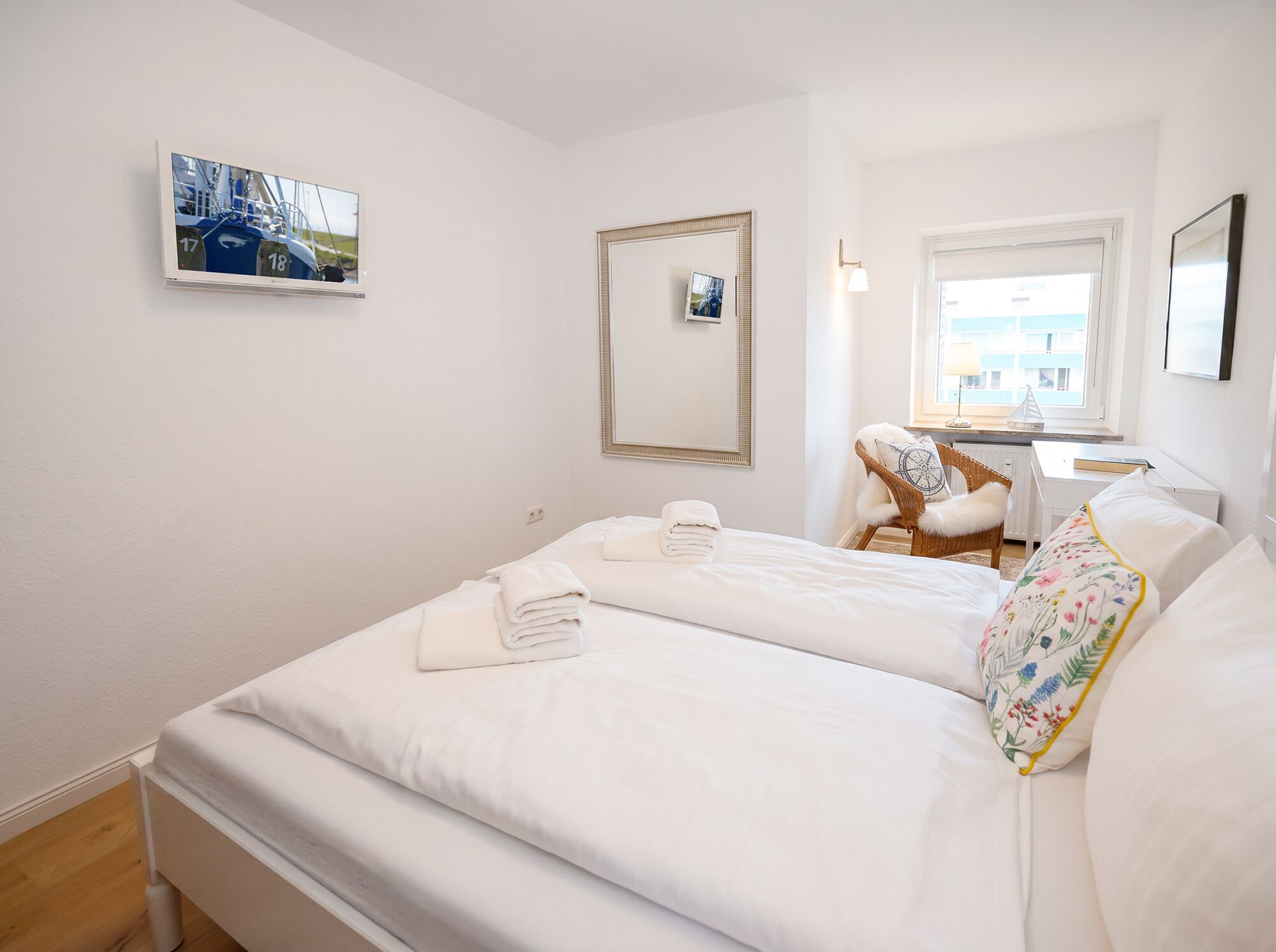 A hotel room with a bed, a chair, a desk, and a window.