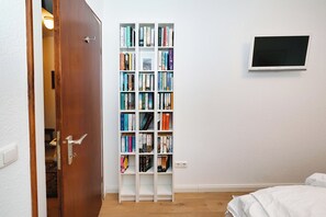 A bedroom with a bookshelf, a bed, and a television mounted on the wall. - "Weitblick" Vacation Rental with Exceptional Ocean Views (Büsum)
