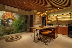 A modern kitchen with a wooden ceiling, a large mural, and a bar area. - Villa Cek Ombak 2 (Badung)