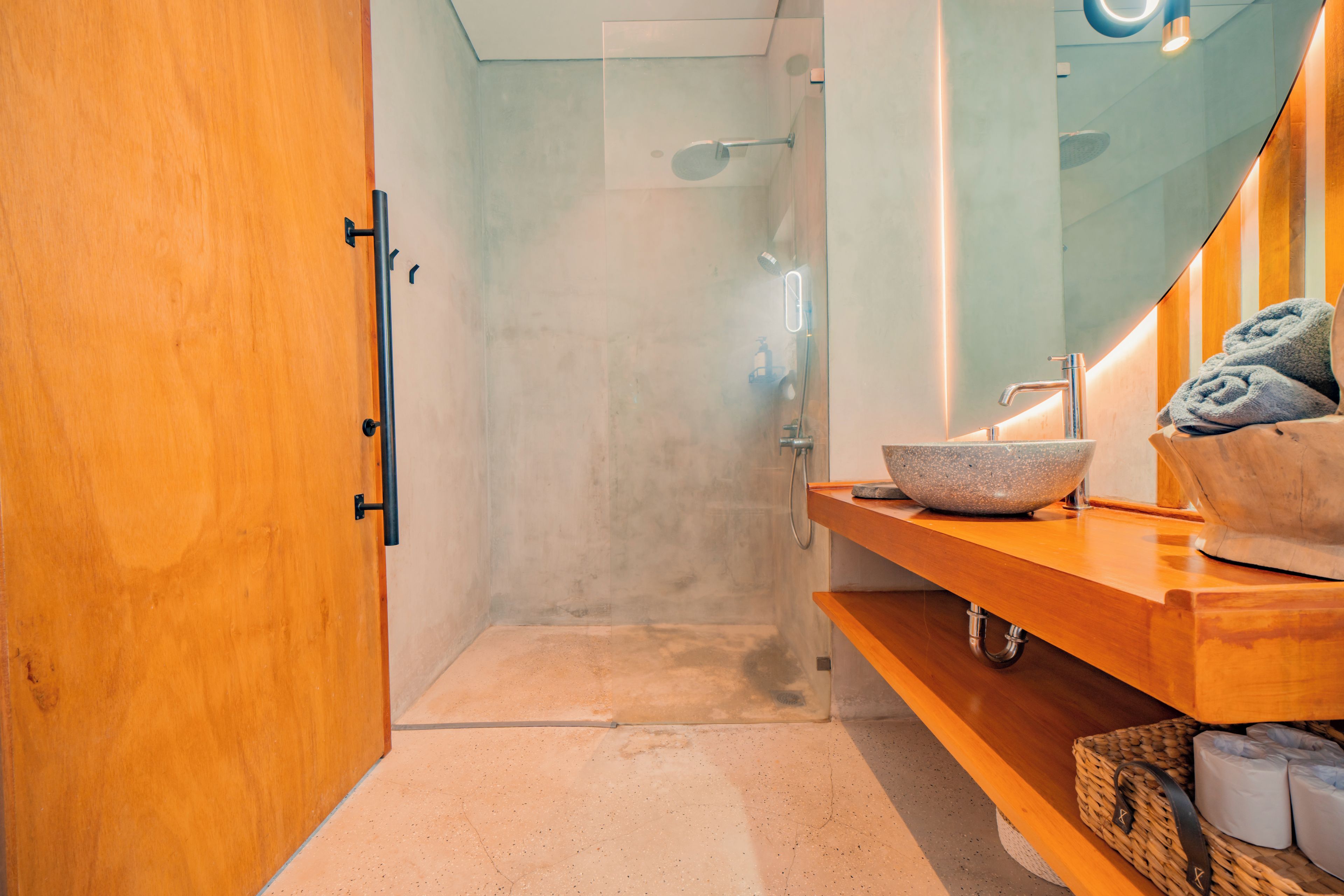 A modern bathroom with a wooden vanity, a large mirror, and a shower area.