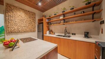 A modern kitchen with wooden shelves, a countertop, and a decorative wall panel.