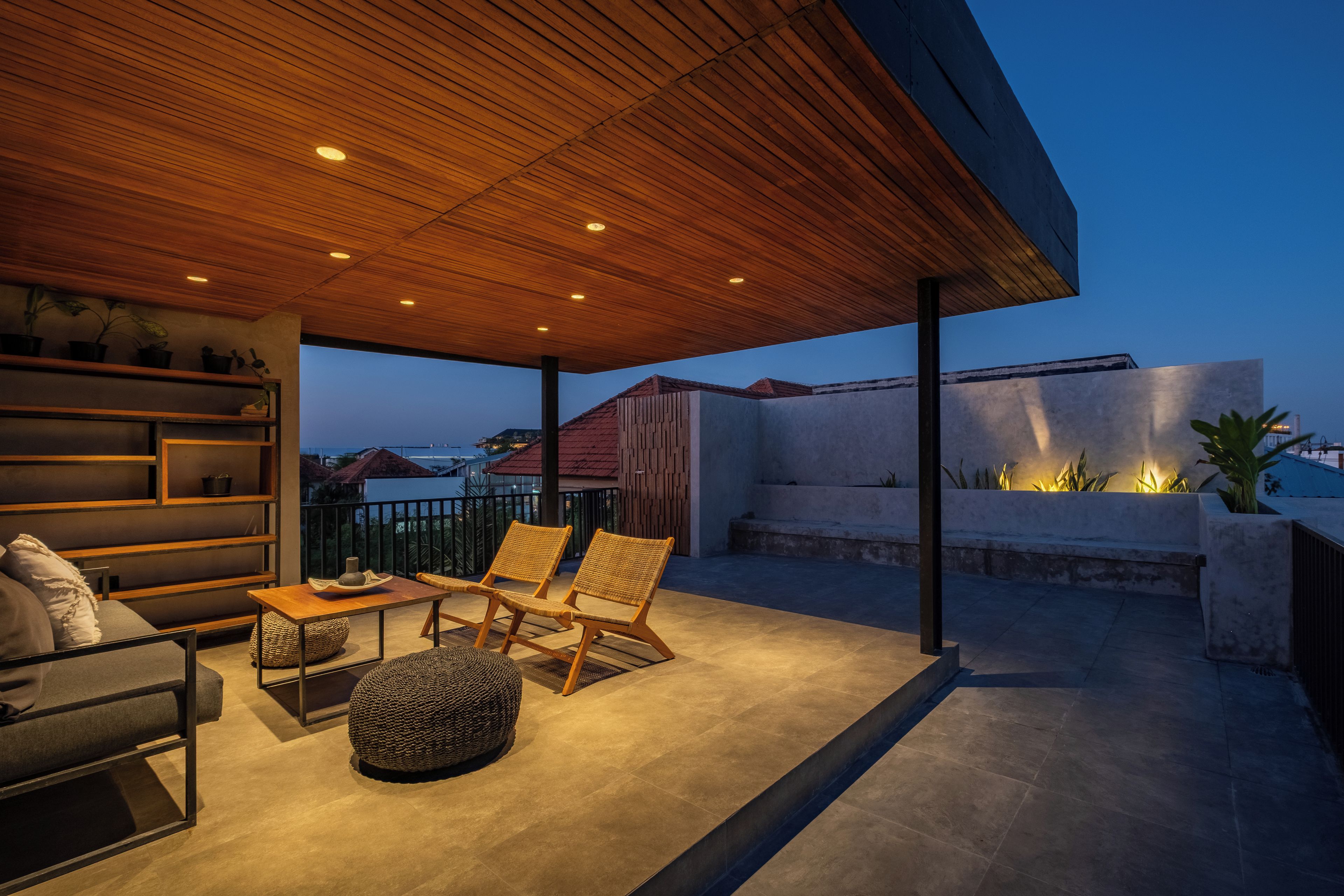 Un espacio de estar al aire libre con techo de madera, un sofá, dos sillones y una mesa.