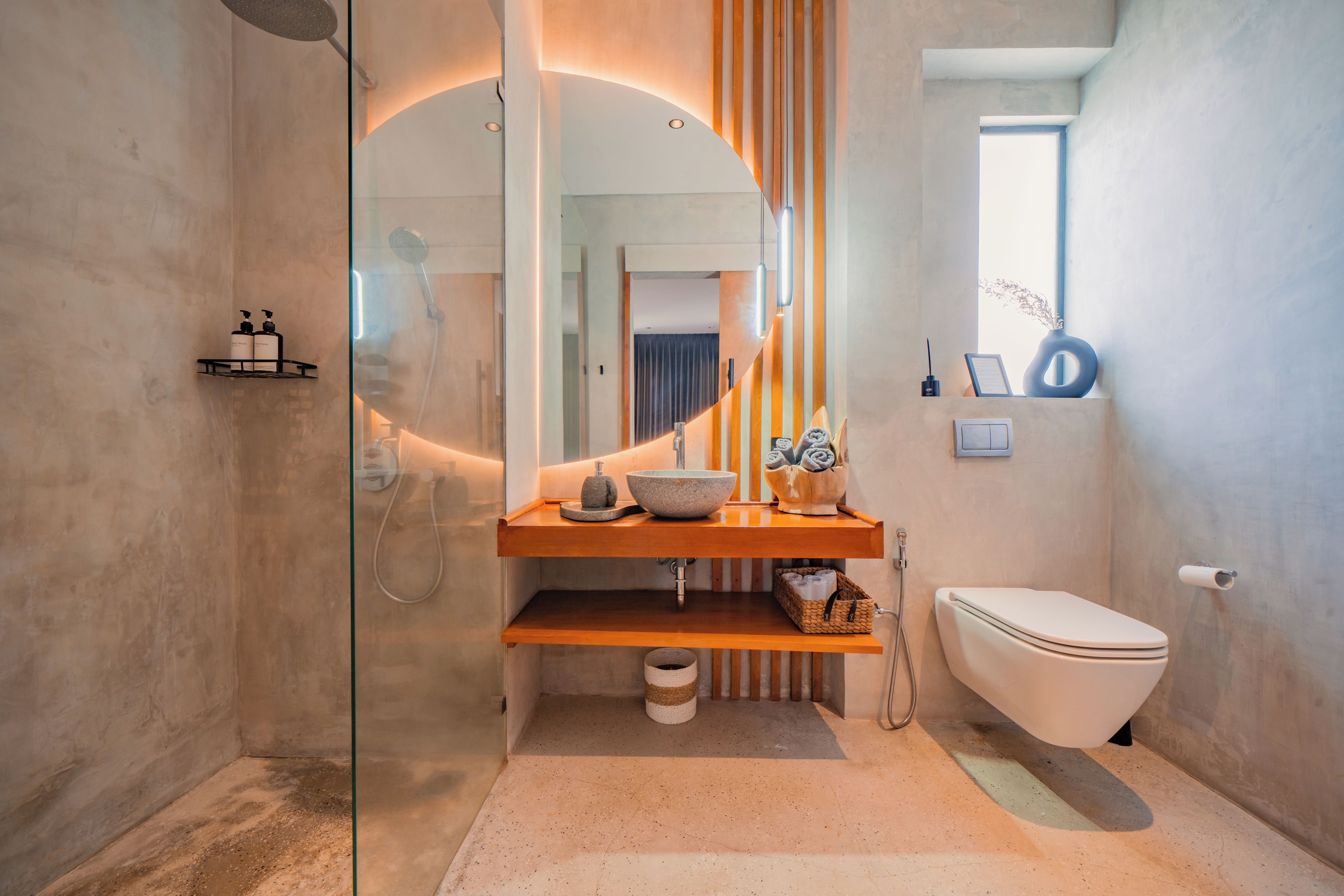 A modern bathroom with a glass-enclosed shower, a wooden vanity with a bowl sink, and a white toilet.