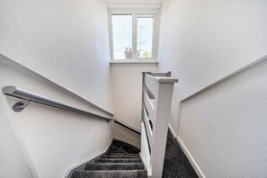 Eine Treppe mit Geländer, einem Fenster und Blick ins Freie.
