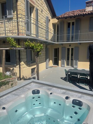 Un bain à remous doté de plusieurs jets, un balcon avec une balustrade et un bâtiment en pierre avec des volets.