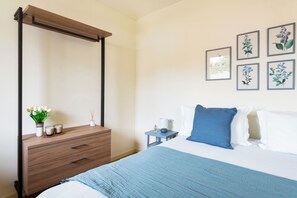 Ein Schlafzimmer mit Himmelbett, einem Holzschrank, einem Nachttisch und Wandbildern.