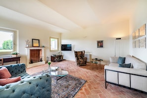 Ein geräumiges Wohnzimmer mit Kamin, Fernseher und einer gemütlichen Sitzecke.