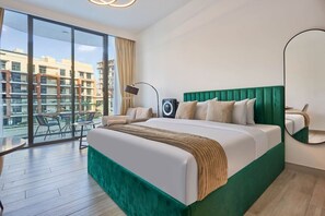 Ein Hotelzimmer mit einem großen Bett, einem Balkon mit Stühlen und Blick auf Gebäude.