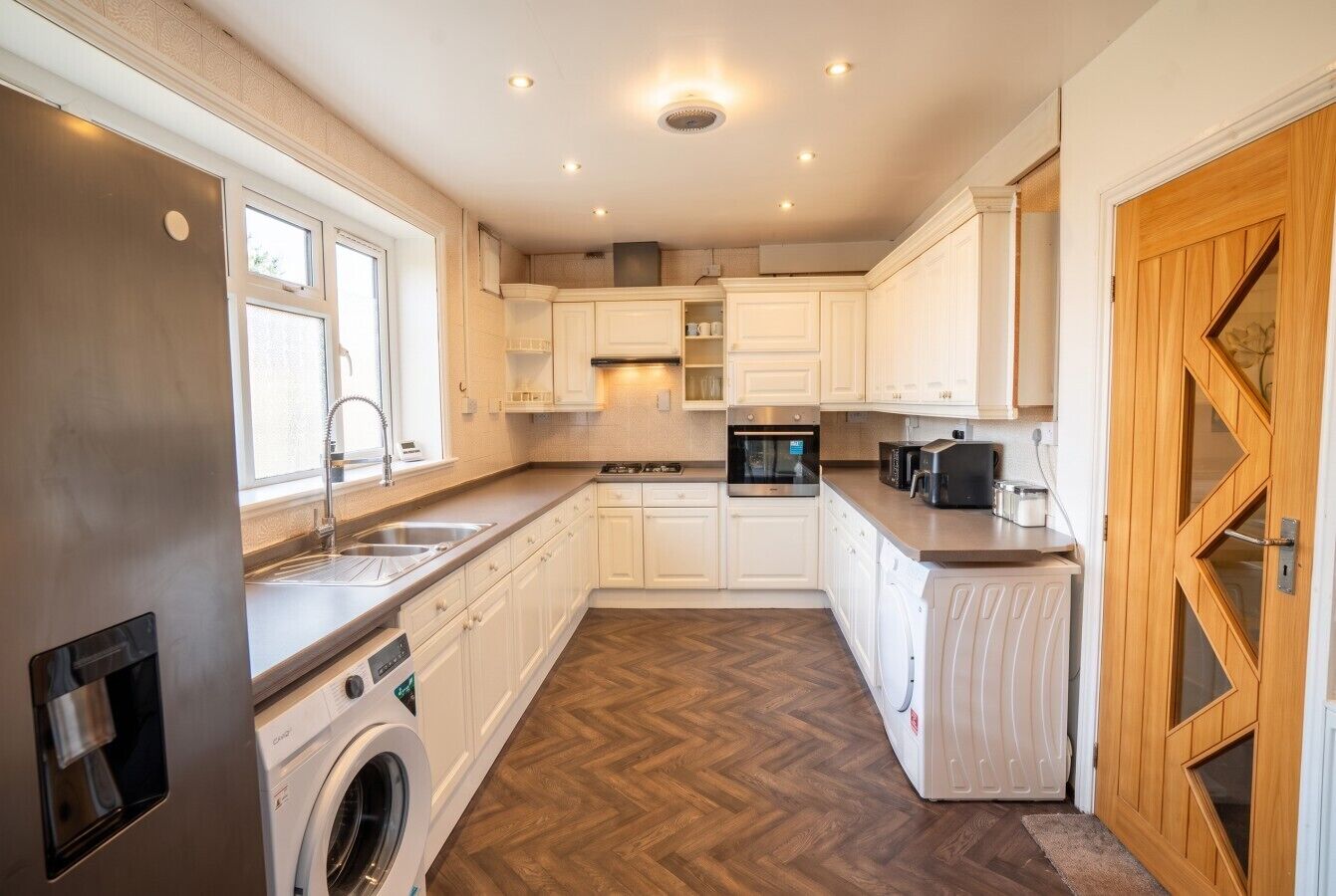 A compact kitchen with built-in appliances, a washing machine, and a microwave.