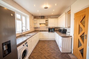 A compact kitchen with built-in appliances, a washing machine, and a microwave.