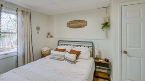 Ein Schlafzimmer mit Bett, Nachttisch, Wanddekoration und einem Fenster mit Vorhängen.