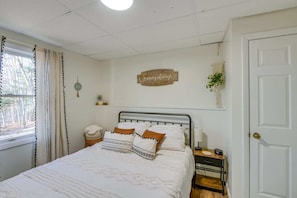 A bedroom with a bed, bedside table, wall decor, and a window with curtains. - Tranquil Woodland Retreat (Glenburn)