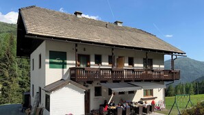 A two-story building with a balcony, a sign reading 'rockalm cottage,' and a paved outdoor area with tables and chairs. - Nockalm Cottage Apartment 5 Kaiserburg Superior (Sankt Oswald)