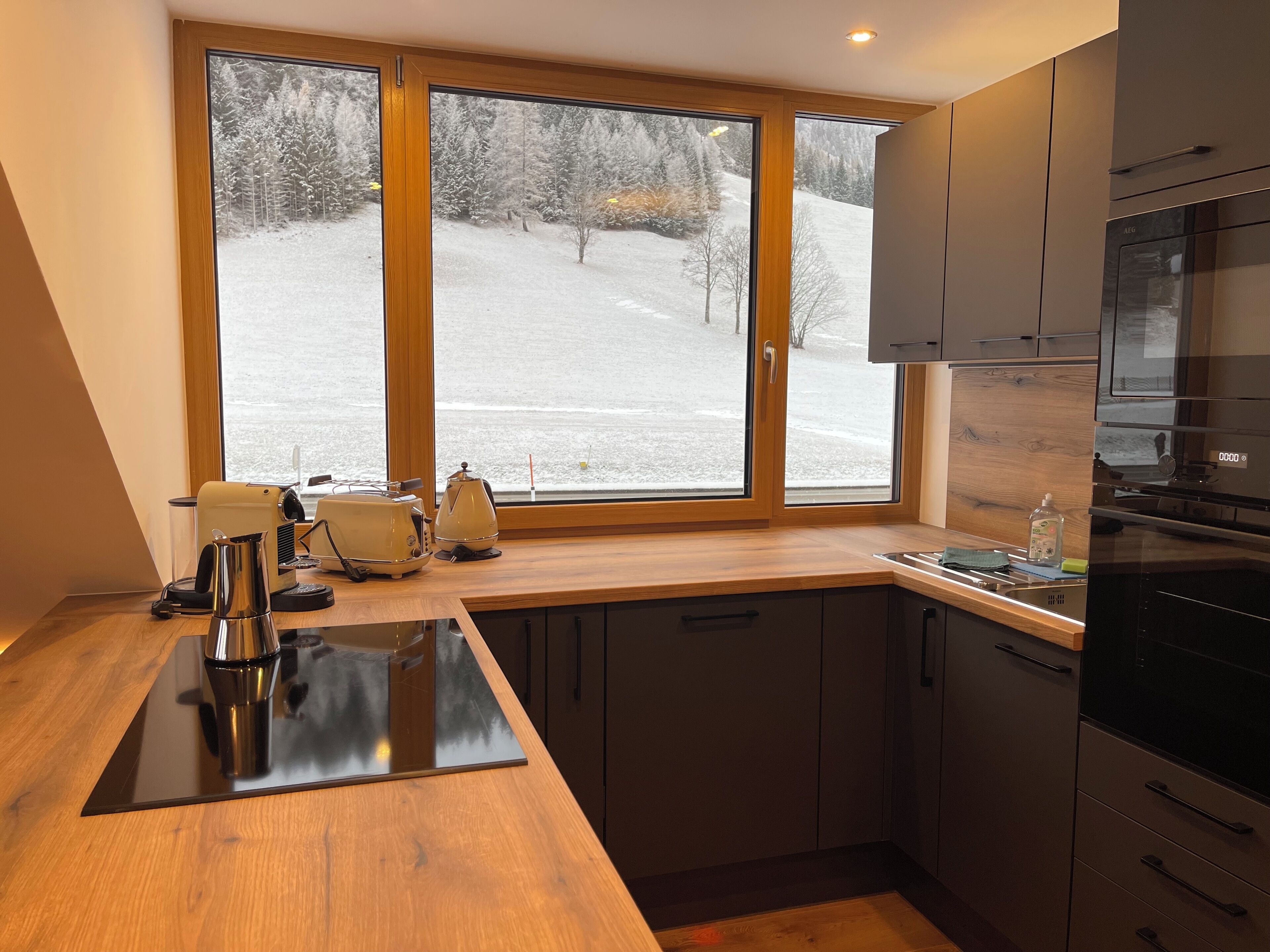 A modern kitchen with a large window, a built-in oven, and a coffee maker.