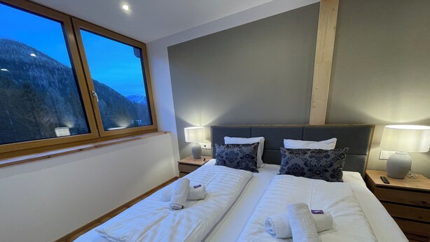 A hotel room with two beds, a large window, and a mountain view. - Nockalm Cottage Apartment 5 Kaiserburg Superior (Sankt Oswald)