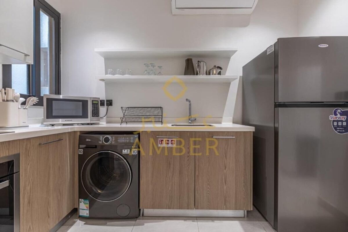 A compact kitchen with a washing machine, microwave, and refrigerator.