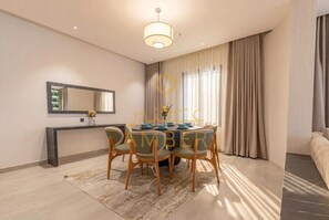 A modern dining area with a round table, chairs, and a pendant light. - Amber Hospitality - AlQuds (Al Quds/ Riyadh)