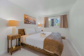 A bedroom with a bed, two bedside tables, a window with curtains, and a painting on the wall. - Tree Top Verdon 5BDR with Sauna (South Lake Tahoe)