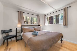 A bedroom with a bed, a chair, two bedside lamps, and windows with curtains. - Tree Top Verdon 5BDR with Sauna (South Lake Tahoe)