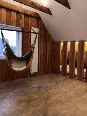 A room with wooden walls, a hammock, a bed, and a window. - Apartment 3 in the Flechtner Building (Norderney)